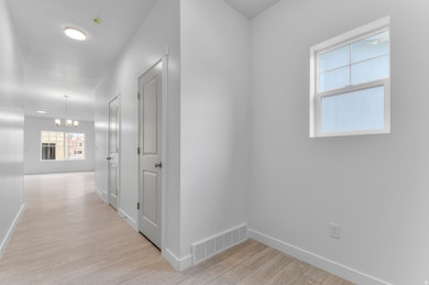 Corridor with light wood-style flooring and a chandelier