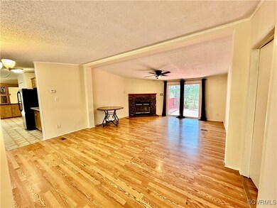  light wood-type flooring, ceiling fan, a fireplace, and a textured ceiling