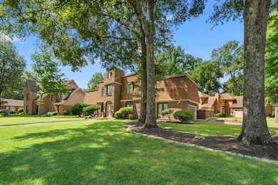 View of front of home with brick siding, a front yard, and a garage