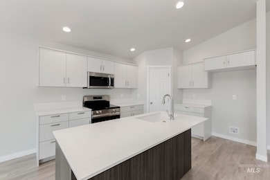 Kitchen featuring stainless steel appliances, light wood-style floors, an island with sink, white cabinets, and recessed lighting