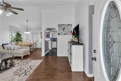 Foyer entrance featuring dark wood-type flooring, ceiling fan, high vaulted ceiling, and a chandelier
