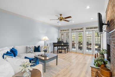Living room featuring french doors, light wood-type flooring, ornamental molding, ceiling fan, and a fireplace