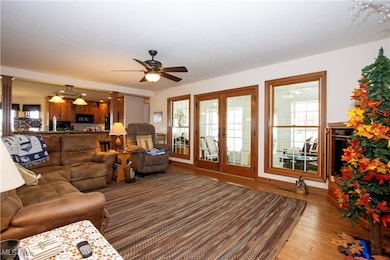 Living room featuring wood-type flooring, french doors, and ceiling fan
