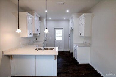 Kitchen featuring dark hardwood / wood-style floors, white cabinetry, sink, and decorative light fixtures