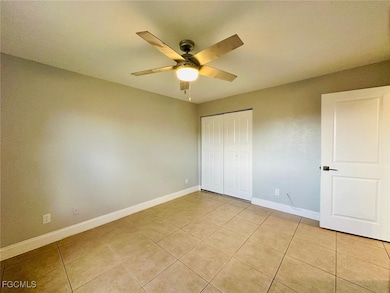Unfurnished bedroom with ceiling fan, light tile patterned flooring, and a closet