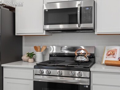 Kitchen with appliances with stainless steel finishes, white cabinetry, and light stone counters