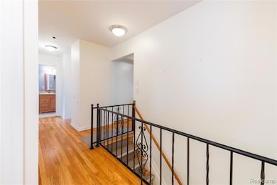 Hall featuring an upstairs landing and light wood finished floors