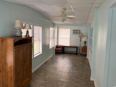 Corridor with a drop ceiling, an office area, a wall mounted air conditioner, lofted ceiling, and wooden walls