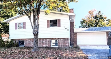View of front facade featuring driveway, an attached garage, and a chimney