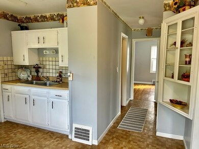 Kitchen featuring washbasin, white cabinetry, backsplash, and countertops light