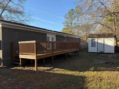 Rear view of house featuring brick siding, a shed,