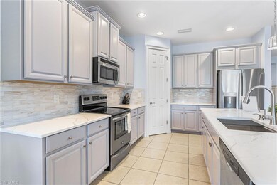 Kitchen featuring appliances with stainless steel finishes, gray cabinetry, a sink, light stone countertops, and decorative backsplash