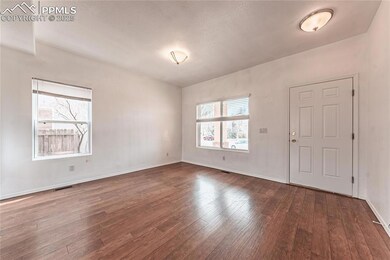 Unfurnished room with dark wood-style floors, visible vents, and baseboards