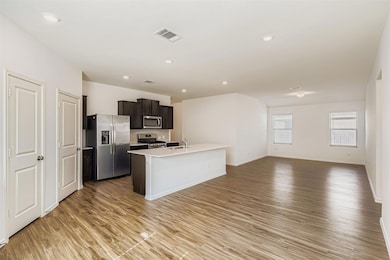 Kitchen featuring stainless steel appliances, open floor plan, light wood-type flooring, a kitchen island with sink, and recessed lighting