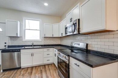 Kitchen with light wood-type flooring, stainless steel appliances, and white cabinetry