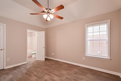 Unfurnished bedroom with connected bathroom, hardwood / wood-style flooring, and ceiling fan