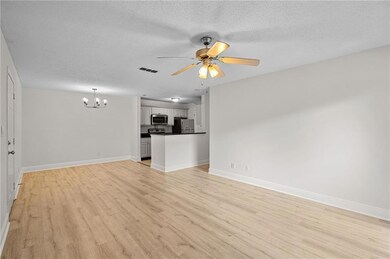 Unfurnished living room featuring a chandelier, light wood-style floors, a ceiling fan, and a textured ceiling