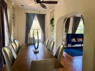 Dining area featuring healthy amount of natural light, built in shelves, a textured wall, a ceiling fan, and dark wood-style flooring
