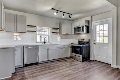 Kitchen featuring appliances with stainless steel finishes, dark hardwood / wood-style floors, a wealth of natural light, and sink