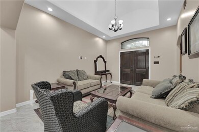 Living room with an inviting chandelier, light tile floors, a high ceiling, and a raised ceiling
