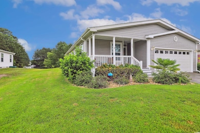 Ranch-style house featuring covered porch, an attached garage, a front yard, and driveway