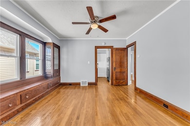 Unfurnished room featuring light wood-type flooring, baseboards, visible vents, ceiling fan, and ornamental molding