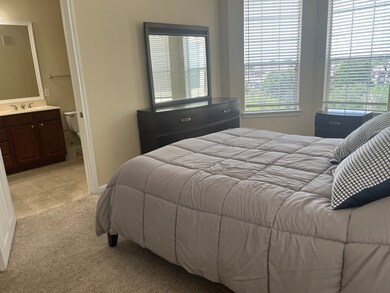 Spacious primary bedroom with queen bed, dresser w