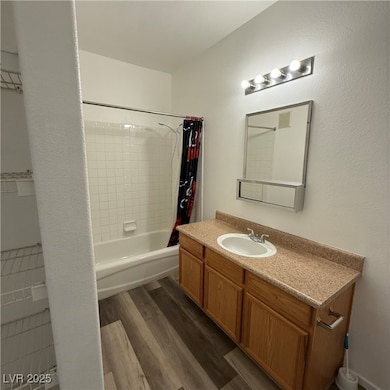 Bathroom with shower / tub combo with curtain, dark wood-style flooring, vanity, and a textured wall