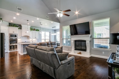 Living room featuring a ceiling fan, a glass covered fireplace, high vaulted ceiling, dark wood-style flooring, and recessed lighting