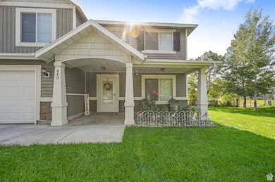 View of front facade featuring a porch, stone siding, a front lawn, a garage, and board and batten siding