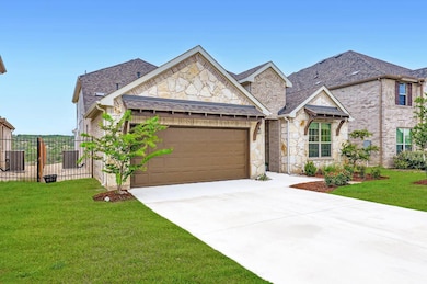 View of front facade featuring stone siding, an attached garage, concrete driveway, a shingled roof, and brick siding