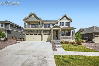 View of front of home featuring covered porch, driveway, stone siding, a garage, and a balcony