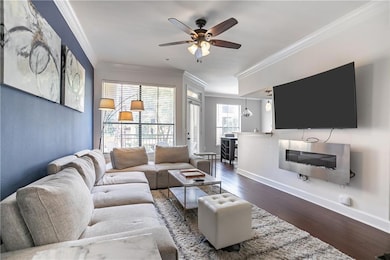 Living area with ornamental molding, dark wood finished floors, and a ceiling fan
