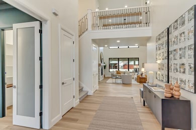 Hallway with recessed lighting, a towering ceiling, light wood finished floors, and stairway