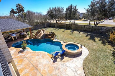 View from upstairs balcony showing the pool, hot tub, waterfall, slide, outdoor kitchen, no rear neighbors, plenty of pool decking for lounging in the sun and plenty of lawn for the kids and/or pets to play.