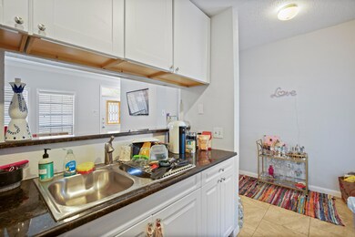 Kitchen with white cabinets, a sink, light tile p