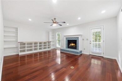 Unfurnished living room featuring a brick fireplace, dark wood-style flooring, recessed lighting, ceiling fan, and built in shelves