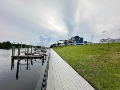 View of dock with a lawn and a water view