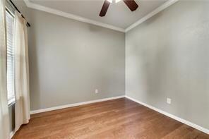 Spare room with ceiling fan, ornamental molding, and dark wood-type flooring