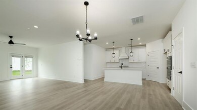 Unfurnished living room featuring a sink, recessed lighting, ceiling fan, light wood-style flooring, and a chandelier
