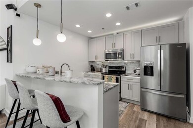Kitchen featuring appliances with stainless steel finishes, a breakfast bar, a peninsula, recessed lighting, and light wood-style flooring