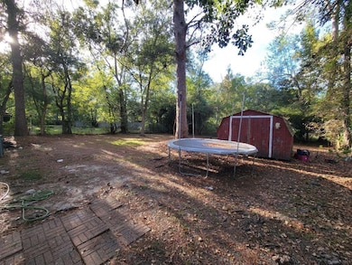 View of yard featuring a trampoline and a storage shed