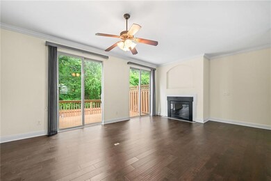 Unfurnished living room featuring a glass covered fireplace, ornamental molding, ceiling fan, dark wood-style flooring, and baseboards