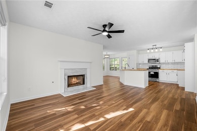 Unfurnished living room with dark wood-style floors, a high end fireplace, a textured ceiling, ceiling fan, and a chandelier