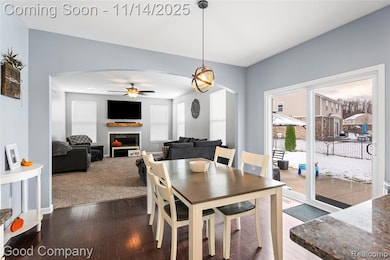 Dining space featuring arched walkways, a fireplace, wood-type flooring, and ceiling fan