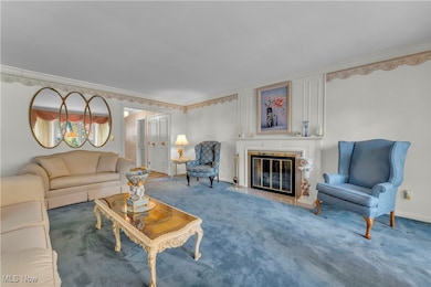 Carpeted living area featuring a glass covered fireplace and crown molding