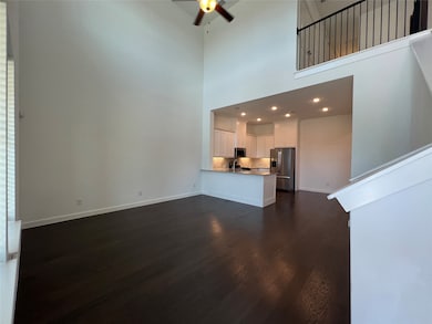 Unfurnished living room featuring a towering ceiling, dark wood-type flooring, and ceiling fan