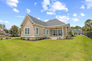 Rear view of property with a lawn, stucco siding, ceiling fan, and covered porch