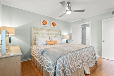 Bedroom with crown molding, a textured ceiling, wood finished floors, and ceiling fan