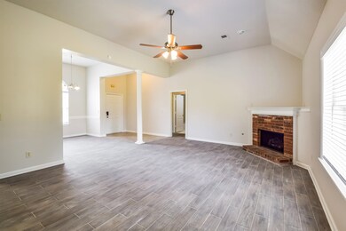 Unfurnished living room featuring dark wood finished floors, a fireplace, ceiling fan, vaulted ceiling, and ornate columns
